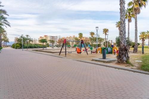 a playground in a park with palm trees at Tirreno 304 in La Pineda