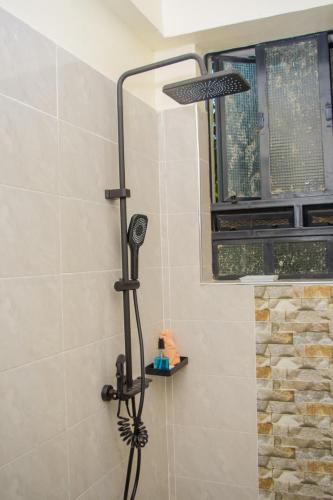 a shower with a shower head in a bathroom at The Loch Hotel Bondo in Bondo