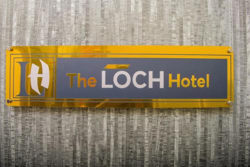 a sign for the lock hotel hanging on a wall at The Loch Hotel Bondo in Bondo