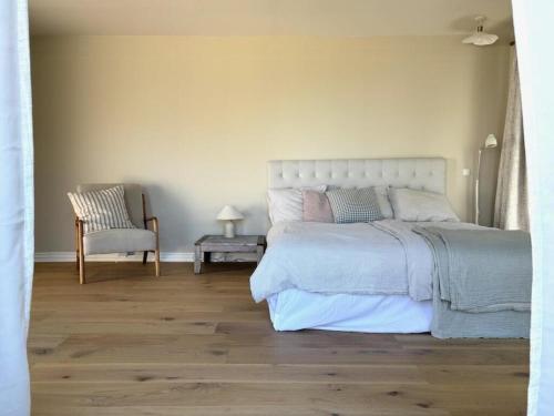 Un dormitorio con una cama grande y una silla. en Boutique Home With Sea View In Vang, en Hasle
