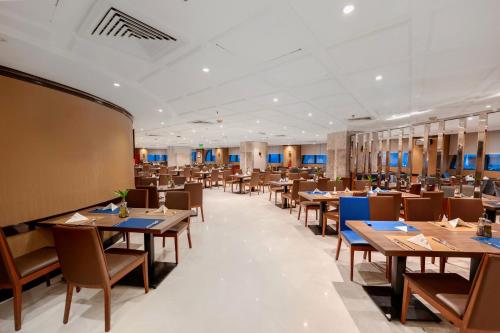 una sala da pranzo con tavoli e sedie in legno di Maysan Al Harithia Hotel a Medina