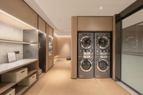 a laundry room with three washer and dryer machines at JI Hotel Beijing South Railway Station North Square in Beijing