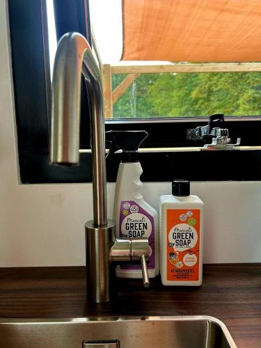 a kitchen sink with a bottle of cleaner next to a faucet at Tiny House De Laro in Hoogstraten