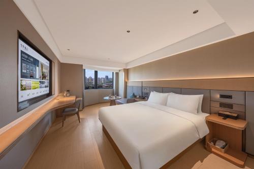 a hotel room with a large bed and a flat screen tv at JI Hotel Beijing South Railway Station North Square in Beijing