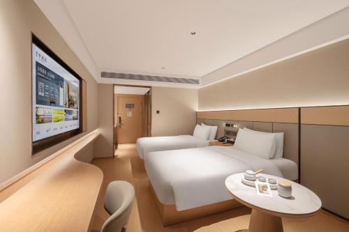 a hotel room with a white bed and a tv at JI Hotel Beijing South Railway Station North Square in Beijing