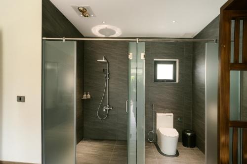 a bathroom with a glass shower and a toilet at Tam Coc Horizon Retreat in Vũ Lâm