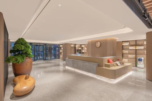 a lobby with a plant in a large vase at JI Hotel Beijing South Railway Station North Square in Beijing