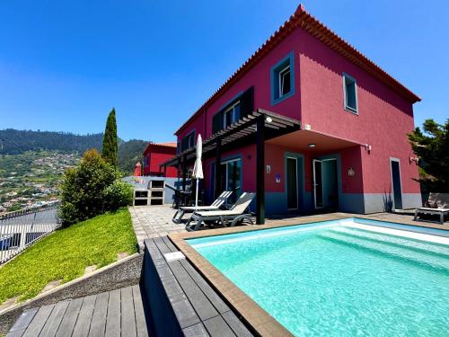 a house with a swimming pool in front of a house at Sunset Dreams - Arco da Calheta in Arco da Calheta