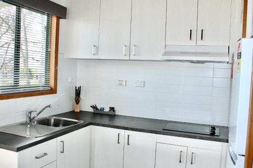 a kitchen with white cabinets and a sink at BIG4 Rutherglen Holiday Park in Rutherglen