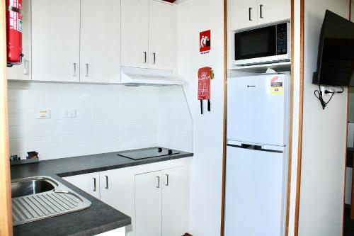 a small kitchen with white cabinets and a white refrigerator at BIG4 Rutherglen Holiday Park in Rutherglen