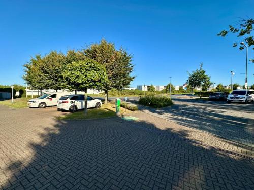 a parking lot with parked cars and a tree at Hotel Landhaus Milser in Duisburg