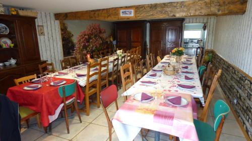 una sala da pranzo con lunghi tavoli con piatti e bicchieri sopra di les pivoines a Cosges
