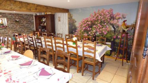 una sala da pranzo con tavoli e sedie e un quadro di les pivoines a Cosges