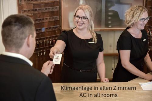 a woman is handing a man a name tag at Hotel Engelhorn in Leimen