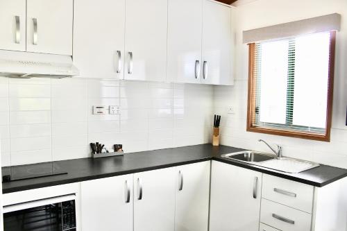 a kitchen with white cabinets and a sink at BIG4 Rutherglen Holiday Park in Rutherglen