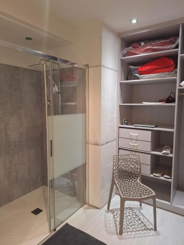 a walkin closet with a chair and a glass shower at Chez Isabelle et Bernard in La Flocellière