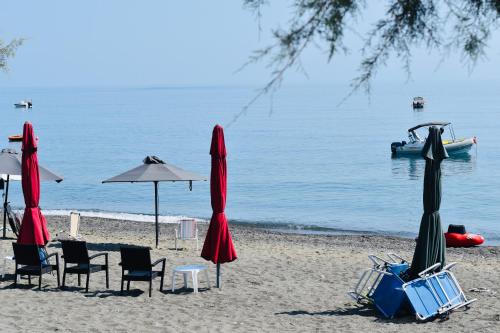 a beach with chairs and umbrellas and a boat in the water at Armonia Seaview Suites in Psari Forada