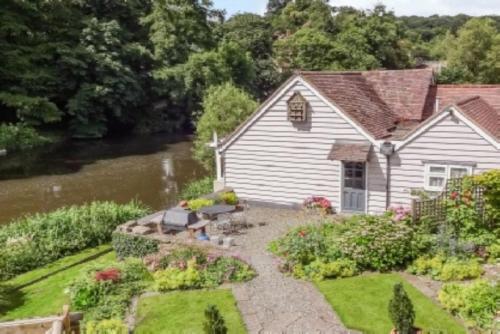 a house with a garden next to a river at The Studio, spacious riverside property in Ludlow with private parking in Ludlow