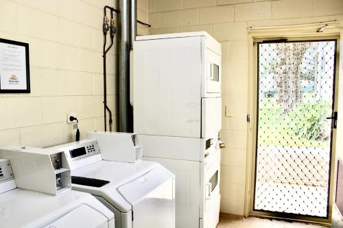 a laundry room with white appliances in front of a door at BIG4 Rutherglen Holiday Park in Rutherglen