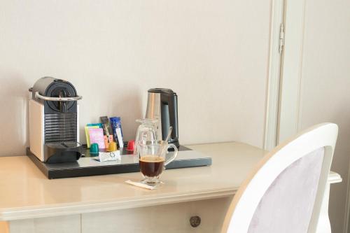 a cup of coffee sitting on a table with a coffee maker at Hôtel Le Maxime - Best Western Signature Collection in Auxerre