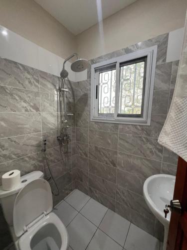 a bathroom with a toilet and a sink and a window at Swett hotel in Kribi