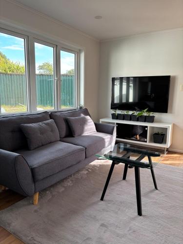a living room with a couch and a tv at Convenient Retreat in Onehunga in Auckland