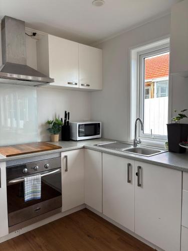 a kitchen with white cabinets and a sink and a microwave at Convenient Retreat in Onehunga in Auckland