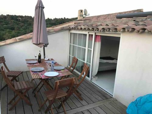 a table and chairs on a deck with an umbrella at Maison confortable à La Garde-Freinet, 160 m², vue ville in La Garde-Freinet