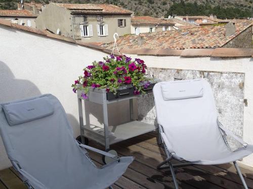 two chairs and a flower planter on a balcony at Maison confortable à La Garde-Freinet, 160 m², vue ville in La Garde-Freinet