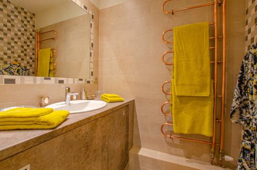 a bathroom with a sink and a mirror and yellow towels at A l'ombre de la cathedrale in Troyes