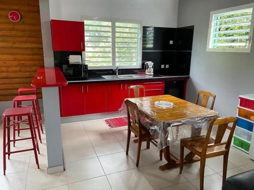 a kitchen with red cabinets and a table and chairs at Appartement spacieux à Sainte-Rose, 70 m² avec jardin in Sainte-Rose