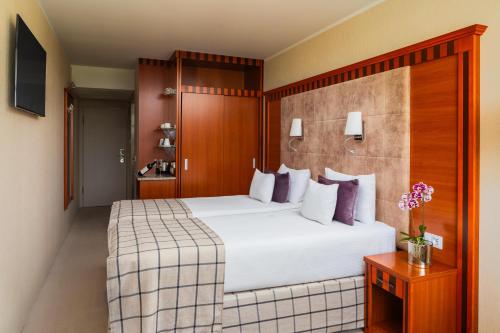 a hotel room with a large white bed with purple pillows at Silvanus Hotel in Visegrád