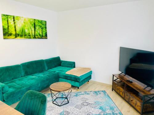 un soggiorno con un divano verde e una TV di Panoramablick Ferien- und Monteurwohnung OG a Mörlenbach