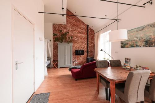 a living room with a dining room table and a brick wall at Mille Fleur Apartments in Voeren