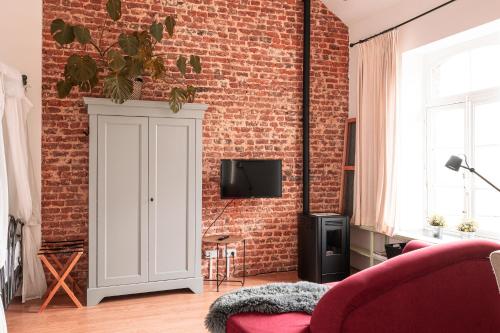 a living room with a brick wall and a white cabinet at Mille Fleur Apartments in Voeren