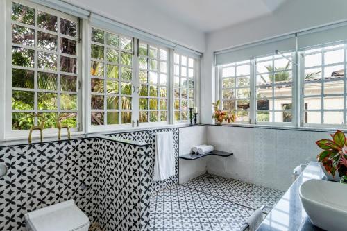 a bathroom with a toilet and a sink and windows at Sereno Pearl 3bhk luxury villa with private pool Assagaon in Assagao