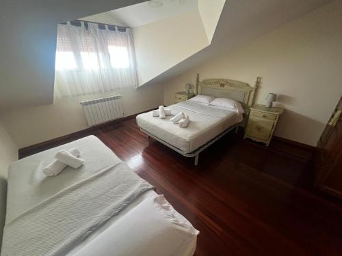 a bedroom with two beds with white sheets at Balcón del Cantábrico in Comillas