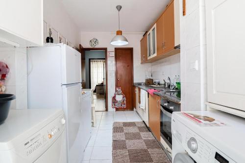 a kitchen with white appliances and a white tile floor at vianahouse in Apúlia