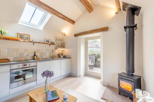 a kitchen and living room with a wood stove at Cosy Barn - Helmsley in Helmsley