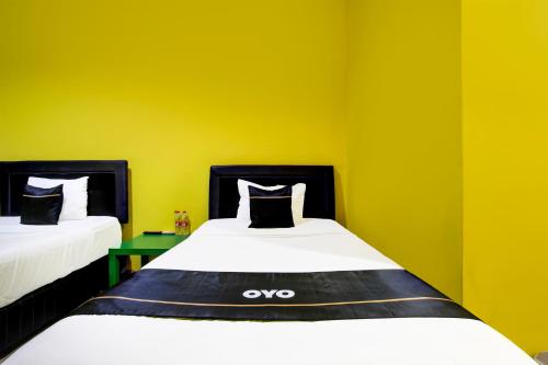 two beds in a room with yellow walls at OYO 94697 Hotel Amanah Sejahtera in Solo