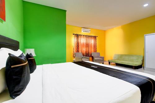 a bedroom with a bed and a green and yellow wall at OYO 94697 Hotel Amanah Sejahtera in Solo