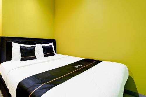 a bedroom with a bed with a yellow wall at OYO 94697 Hotel Amanah Sejahtera in Solo