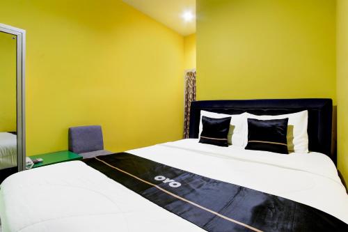 a bedroom with two beds and a yellow wall at OYO 94697 Hotel Amanah Sejahtera in Solo