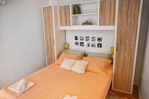 a small bedroom with a bed with orange sheets and pillows at West Wall Apartment in Split
