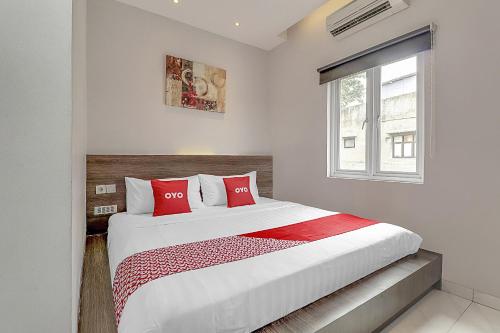 a bedroom with a large bed with red pillows at Capital O 94727 Regia Cihampelas Ciwalk in Bandung