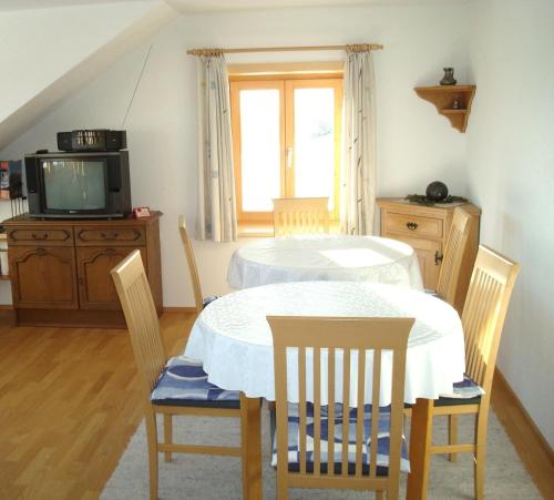 ein Esszimmer mit einem Tisch, Stühlen und einem TV in der Unterkunft Haus Dreiländerblick in Sulzberg