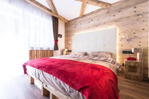 a bedroom with a large bed with a red blanket at Alpstyle Hotel Albolina Wellness & Beauty in Canazei