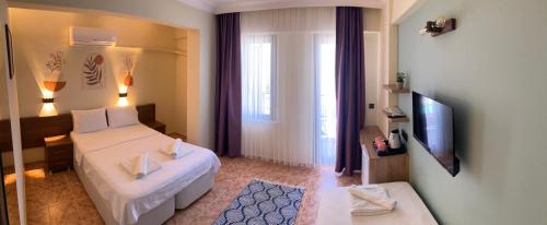 a hotel room with a bed and a television at Olimpia Hotel in Fethiye