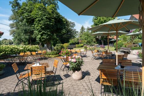 a patio with tables and chairs and an umbrella at Sopherl am See - Frühstück auf der Seeterrasse, sehr ruhig und wunderschön am See, 3 Minuten nach Oberpfaffenhofen, viele Radtouren, Restaurants & Cafes in der Umgebung in Weßling