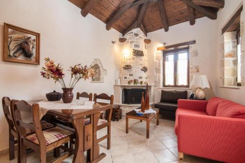 een woonkamer met een tafel en een rode bank bij Eva Traditional Houses in Volimes in Áno Volímai